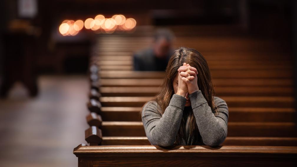 A person prays in a pew in Trinity Church