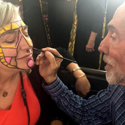 Man paints a woman's face for a Movement Choir production.