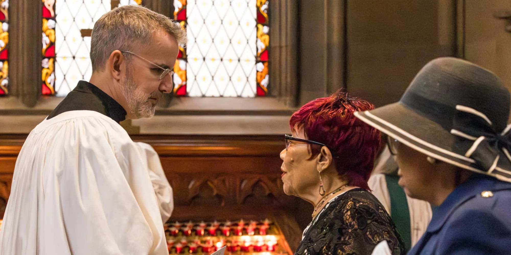 Sacristan talks with two parishioners in Trinity Church after a service.