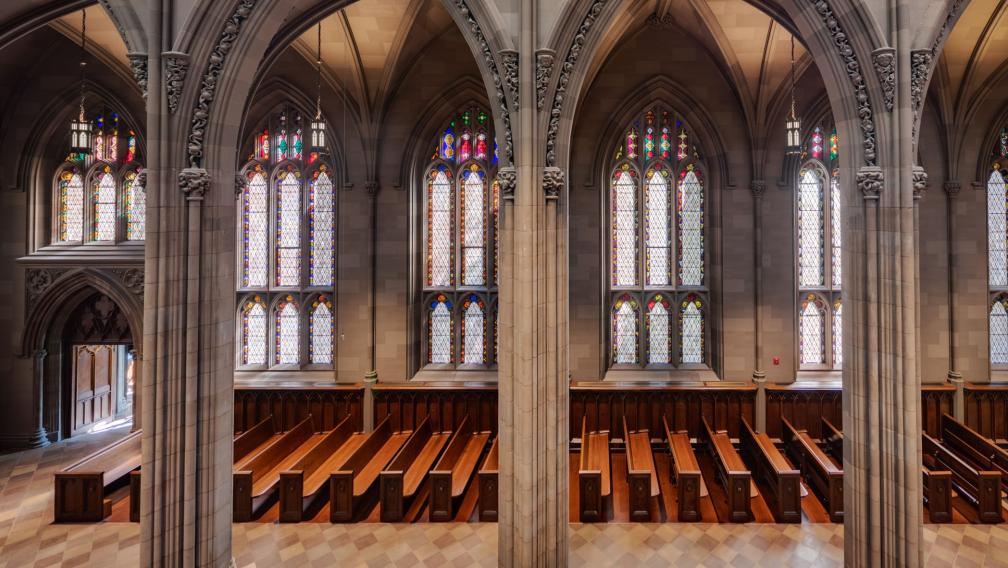 A wide shot of empty pews against a wall of stained glass windows in Trinity Church Wall Street