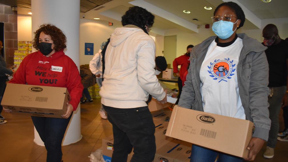 Masked volunteers carry boxes of Barilla at a Trinity Pop-Up.