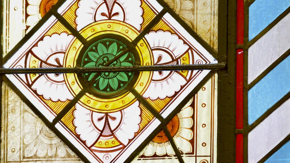 A close-up of a stained glass window in Trinity Church with green and white flowers over a yellow, red, blue, and white background