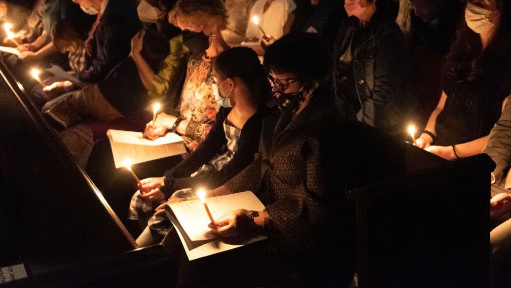 Parishioners holding candles in a dark Trinity Church