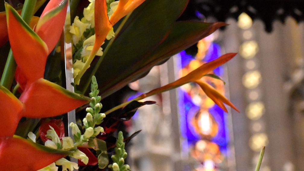Bright orange flowers in front of glowing stained-glass windows in Trinity Church