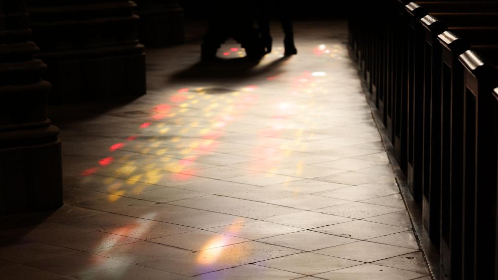 Yellow and red light filters through stained-glass windows and shines on the floor of Trinity Church