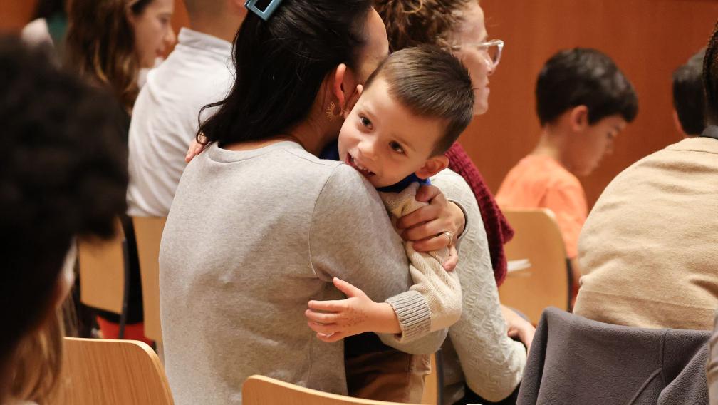 A child hugs their guardian during Family Service at Trinity Commons