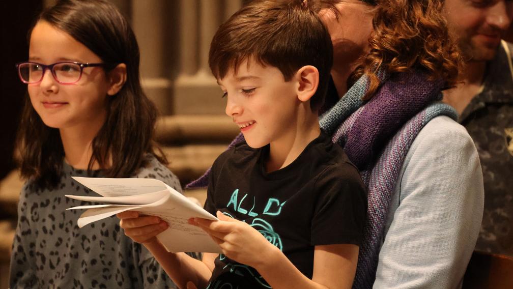 A child reads the worship bulletin with a smile during the 9am service at Trinity Church