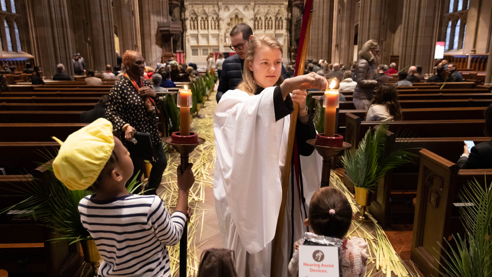 Emily Smith lighting candles for two young parishioners on Palm Sunday, 2023
