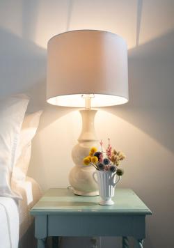 Bedside table with reading lamp and small arrangement of flowers