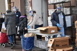 People dressed in PPE give out supplies to Compassion Market attendees.