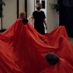 Humankind performance with a red cloth and person reaching