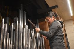 A female organ installer works on the shiny pipes in the new Chapel of All Saints organ.