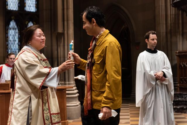 The Rev. Yein Kim gives a baptism candle to David De Hannay 