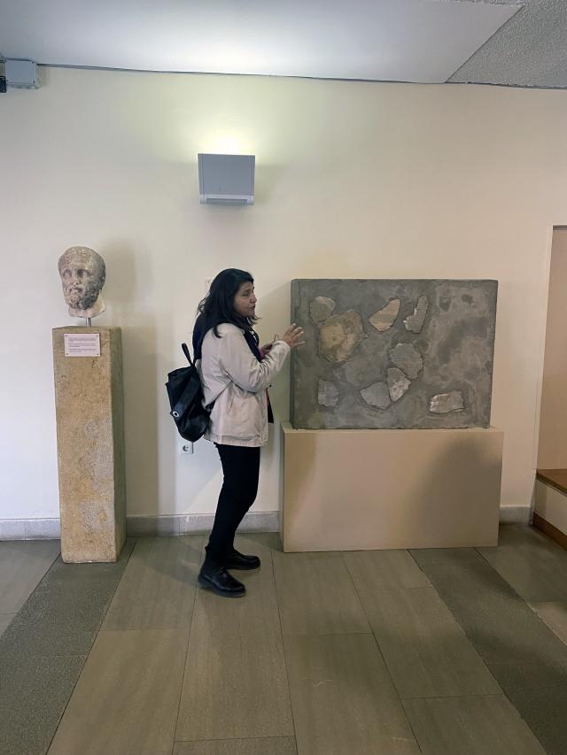 Woman stands beside stone artifacts
