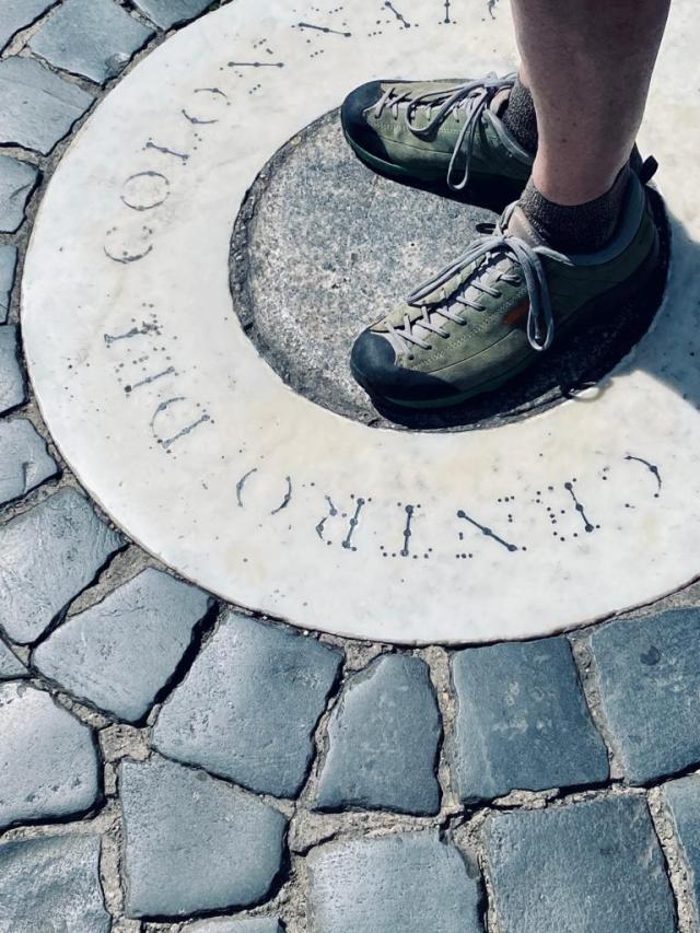 Hiking shoes standing on top of a stone marking the center of a colonnade