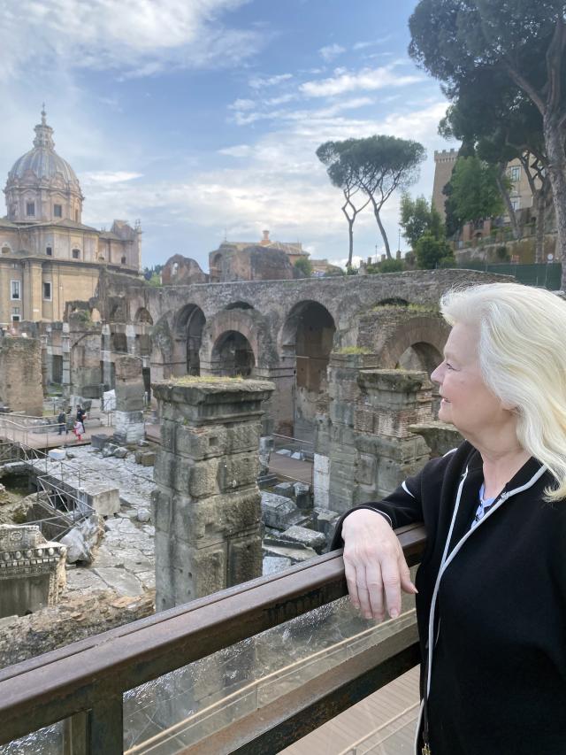 Woman stands at railing looking out over ancient city