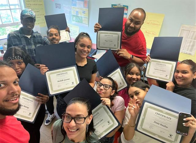 A group of students smile while holding their certificates of completion for Future Now's Medical Terminology course.