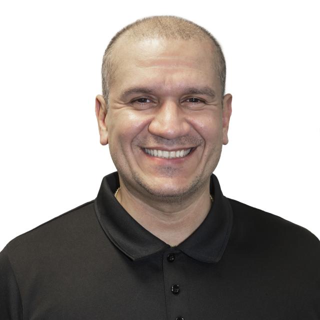 Frank Gonzalez smiles while wearing a black polo shirt.