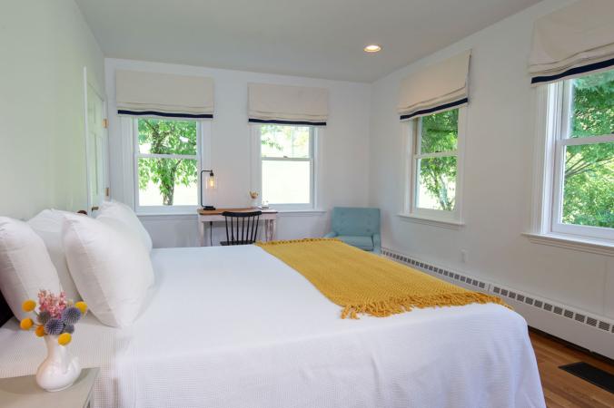 Guest room with queen-sized bed and writing desk with view of the grounds
