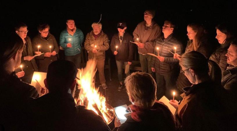 Group sings by candlelight, around the campfire