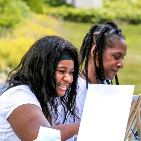 A Black daughter and mother paint side by side at the Community Wellness Retreat in July 2022. 