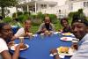 A family enjoys a Fourth of July lunch at round tables in the Retreat Center's yard