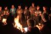Group sings by candlelight, around the campfire