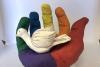 A sculpture of a rainbow-colored hand holding a white dove