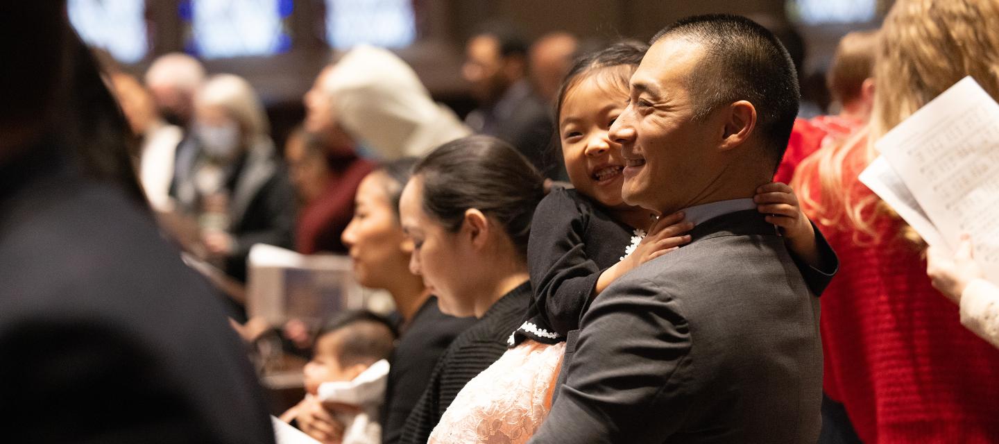 A man is holding a young girl during a service at Trinity Church