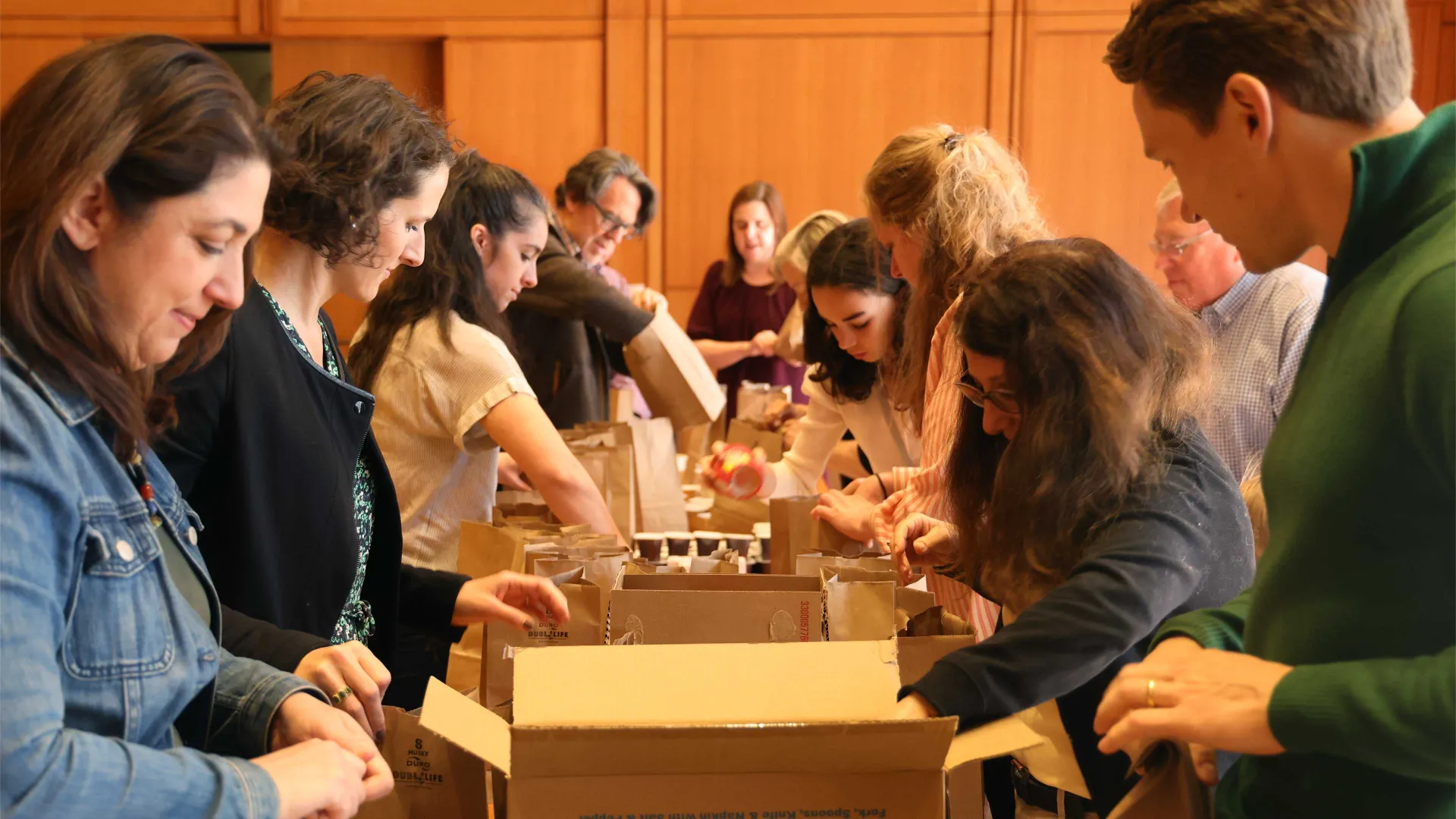 People on either side of a long table pack bagged lunches for the Compassion Meals program.