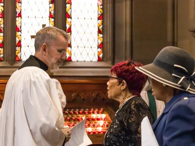 Sacristan talks with two parishioners in Trinity Church after a service.