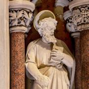 Statue in Trinity Church in marble and plaster, a saint holding a book.