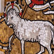 A mosaic of a lamb made up of white, gold, and red tiles on an altar