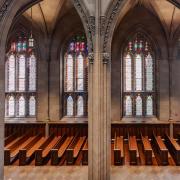A wide shot of empty pews against a wall of stained glass windows in Trinity Church Wall Street