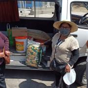 Women stand in front of a van with doors open showing food items