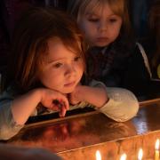 Children look peer onto a table of lit candles in St. Paul's Chapel