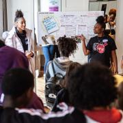 Black girls and LBGTQ+ youth gather in a meeting to discuss a campaign. 