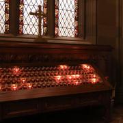 Prayer candles burn beneath a stained-glass window in Trinity Church