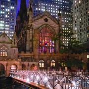 Trinity Church lit up at night with a bridge and stained glass window.