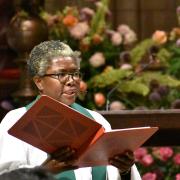 The Rev. Sr. Promise Atelon preaches at Trinity Church with a book in front of flowers