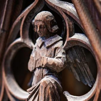 A person kneeling in prayer, depicted on a wood carving in Trinity Church