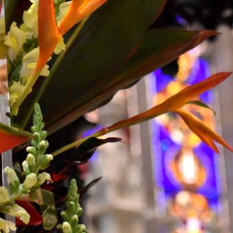 Bright orange flowers in front of glowing stained-glass windows in Trinity Church