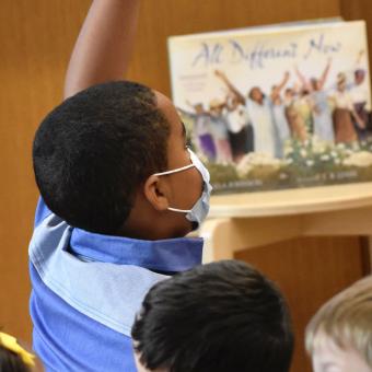 A child raises their hand during Children's Time at Trinity Commons