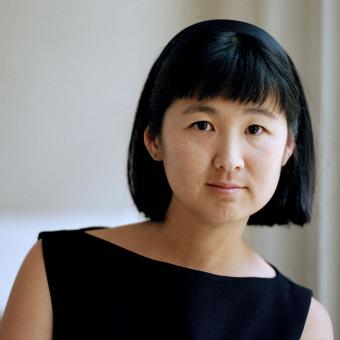 Maya Lin faces the camera wearing a black boatneck top in front of a white backdrop. Her hair is cut in a bob.