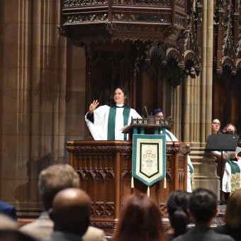 The Rev. Kristin Miles preaches and holds up three fingers at Trinity Church