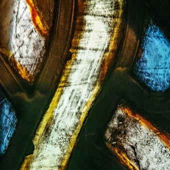 Extreme close up of stained glass with whites, yellows, oranges, and blues