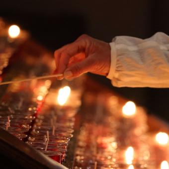 A person reaching to light a candle in Trinity Church