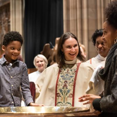 Family smiles at one another in the chancel of Trinity Church with the Rev.Kristin Kaulbach Miles, Regina Jacobs, and the Rev. Dr. Mark Bozzuti-Jones