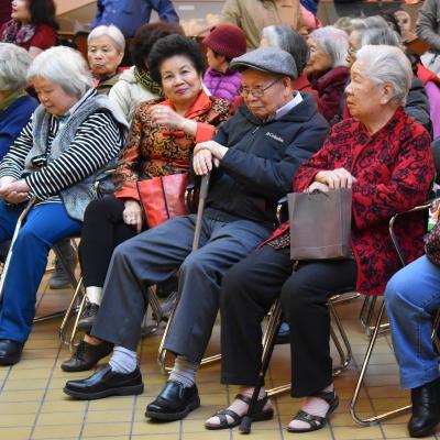 A row of elderly Asian people are seated facing left.