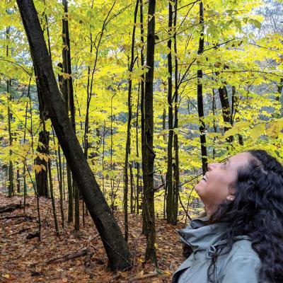 Woman smiling while looking up at trees during a hike